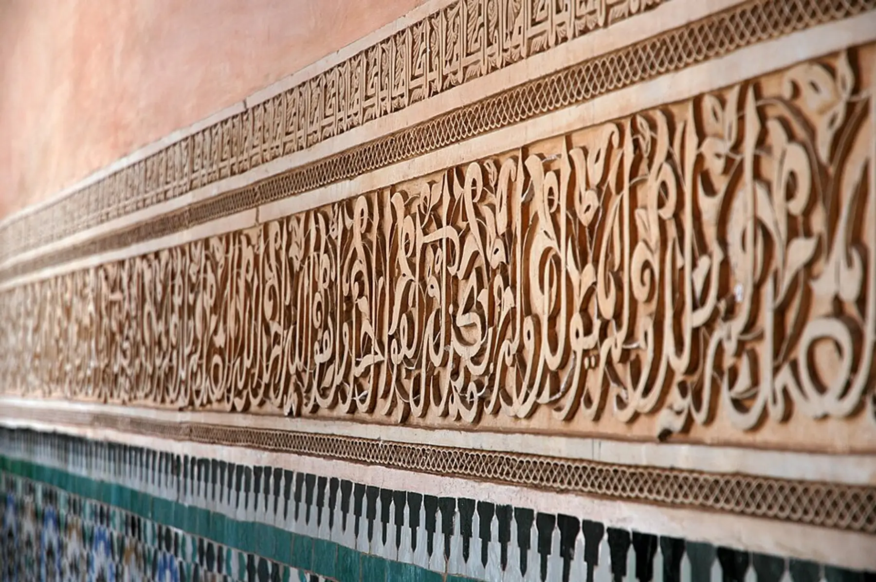 Carved stucco calligraphy and zellige tilework on a wall of the Ben Youssef Medersa