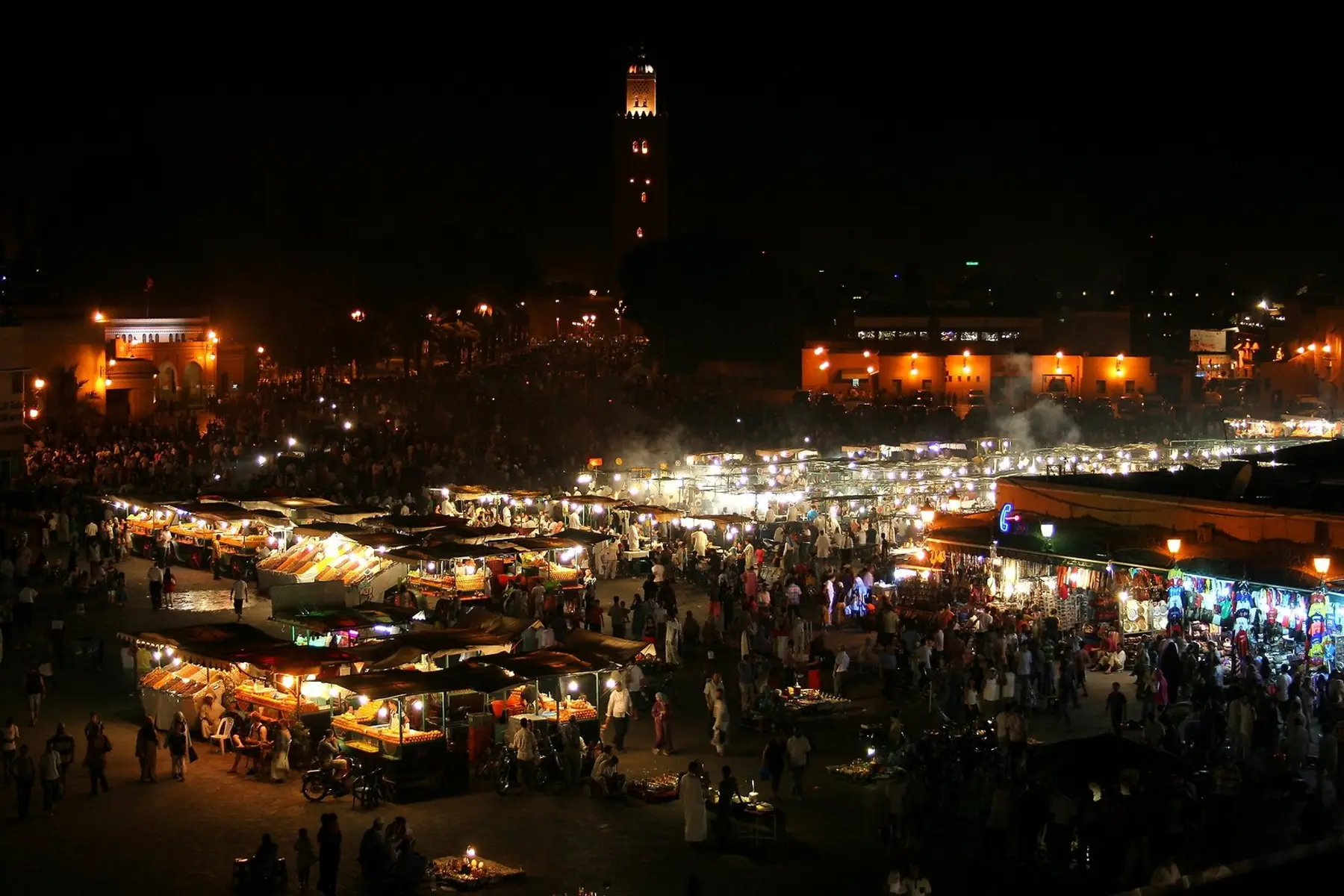 Los puestos de comida de Jemaa el-Fna de noche con el minarete de la Koutoubia detrás